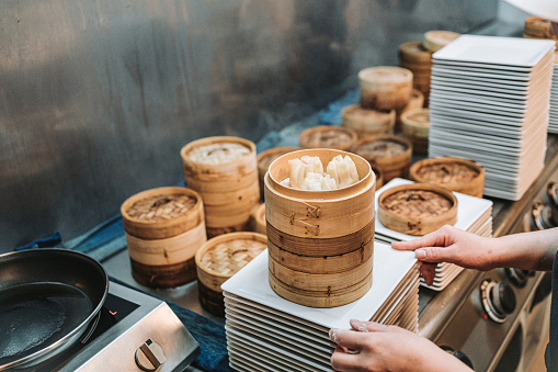 dim sum dumplings steamed in a kitchen restaurant are being stacked and ready to be served