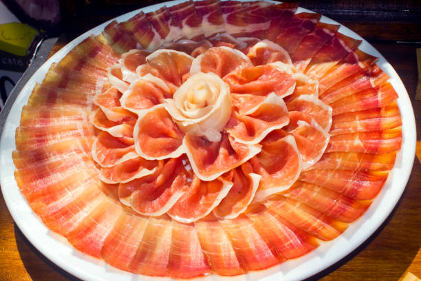 Antequera, Spain - March 12, 2025: A white plate with cured ham, apple, lettuce, and walnut remains. The dish blends sweet and savory in a rustic farm restaurant.