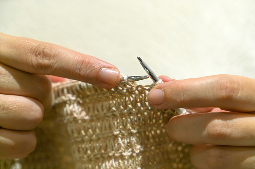 Woman knitting brown threads closeup