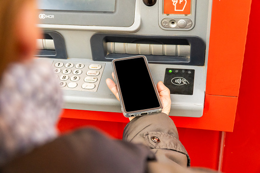 A person connecting the phone via NFC to the ATM
