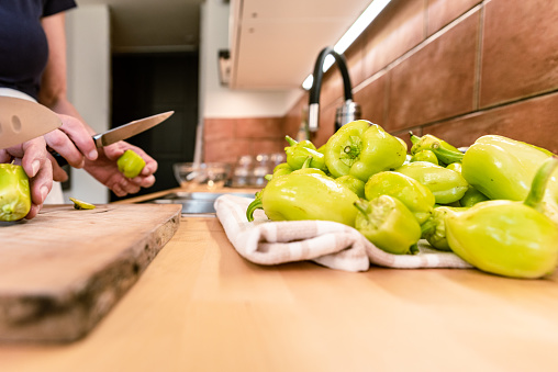Mature Woman in Domestic Kitchen Helping Senior Mother Cleaning Green Pepper for Making Homemade Vegetable Preserves