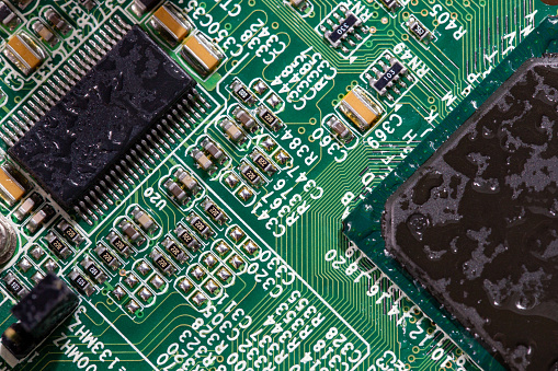 wet digital circuit board with microprocessors and components, closeup full-frame macro background