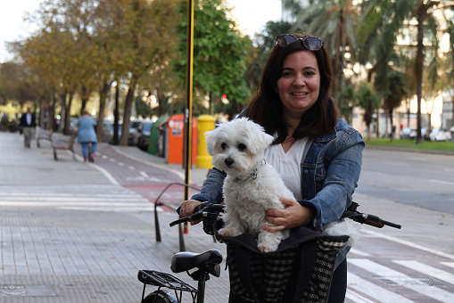 Young lady walking with her dog in bicycle basket