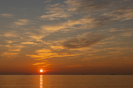 Sun is setting over by the sea, horizon.