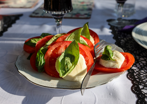 Tasty mozzarella cheese with basil and tomatoes on white plate