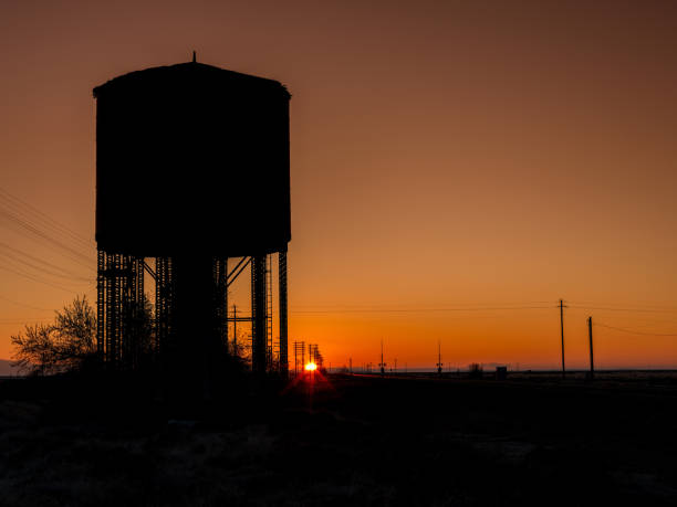 istock Sunrise along a railroad with a water tower silhouette 1845450521
