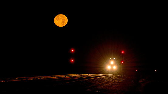 Train lights and tracks at night with a full moon