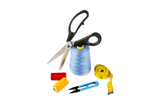 Sewing supplies (thread, scissors and measuring tape) isolated on a white background.