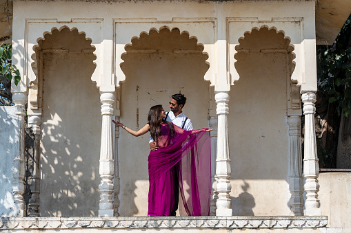 Udaipur, India - Nov 24, 2018 : Happy young couple of Indian guy and girl on the background of a stone palace in city Udaipur, Rajasthan, India