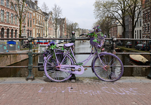 Amsterdam, Netherlands - April 21, 2023: Old lavender colored bicycle on the bridge in De Wallen - called the red light district. It is famous for its entertainment character