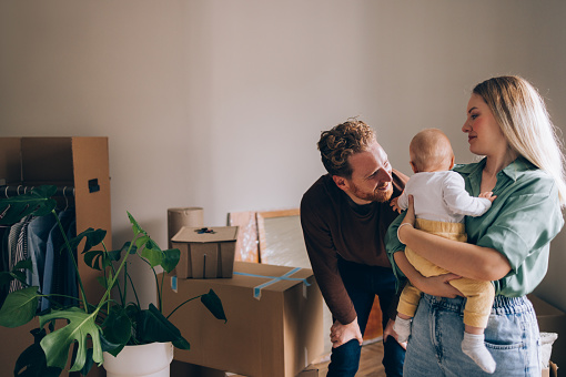 Happy Family With a Baby Moving Into a New Apartment, Boxes All Around