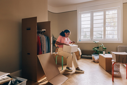 A woman embraces new beginnings, unpacking boxes and transforming her fresh apartment into a space of comfort.