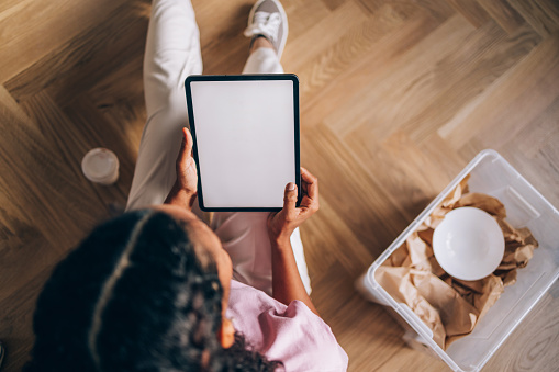 Nestling into her new space, a woman uses a tablet for a digital touch, making her move-in experience modern and efficient.