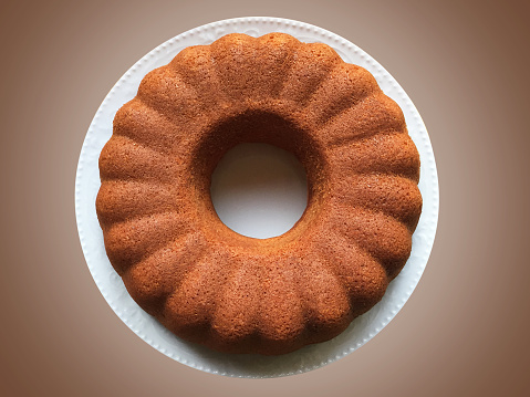Directly above a whole sponge cake in a white plate on colored background with clipping path