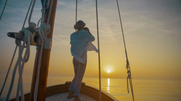 istock Woman looking at sunset through binoculars while standing on sailboat in sea against sky,Istria,Croatia 1845534397