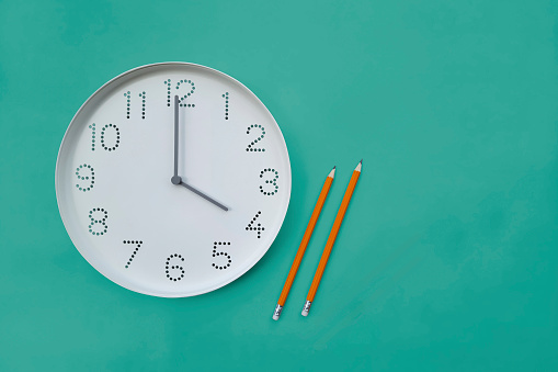 Clock and two pencils on a turquoise background with space for text, to-do list. Four pm on clock face, Thursday. List of to-dos, appointment, meeting. Flat lay, Copy space.