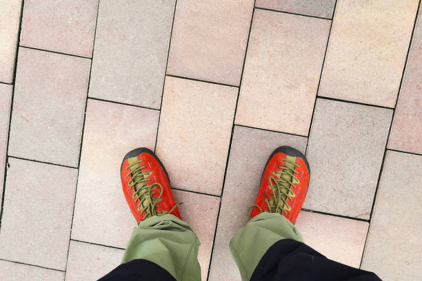 Feet in moccasins stand on sidewalk. View from above.