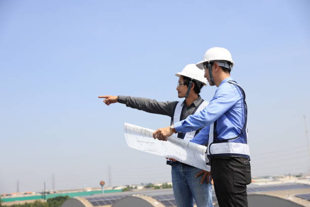 deux hommes ingénieurs portant des gilets de sécurité discutent sur le chantier de construction du toit solaire - 24424 photos et images de collection