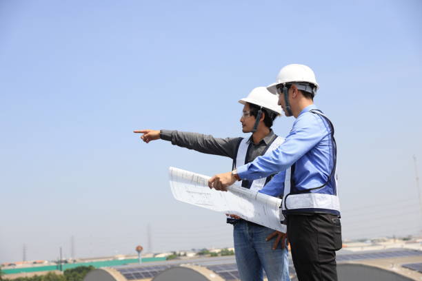 due uomini ingegnere con il piano che indossa giubbotti di sicurezza che parlano sul cantiere del tetto solare - 24424 foto e immagini stock
