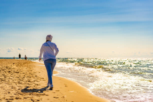 istock Beautiful woman walking on sunny beach 1845636875