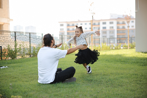 Dad and child  playing in garden, backyard or park for fun. Family, father and girl with hands on face with smile, happiness and game by trees in summer for bonding
