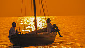Side view of thoughtful couple sitting on silhouette sailboat in seascape during sunset at Istria,Croatia