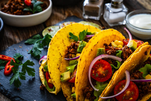 istock Tacos with ground beef, avocado, corn and fresh vegetables on wooden table 1845651009