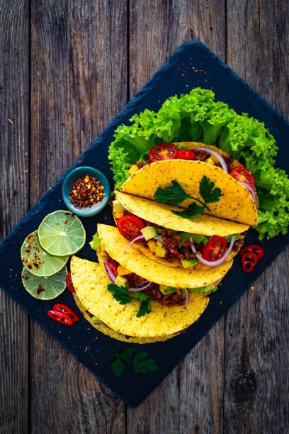 istock Tacos with ground beef, avocado, corn and fresh vegetables on wooden table 1845652069