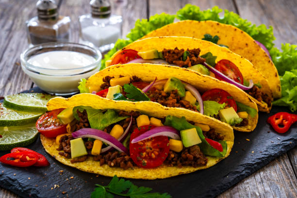 istock Tacos with ground beef, avocado, corn and fresh vegetables on wooden table 1845652846