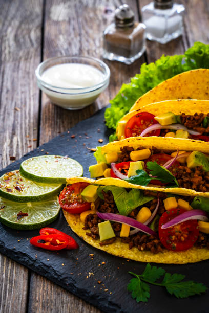 istock Tacos with ground beef, avocado, corn and fresh vegetables on wooden table 1845653098