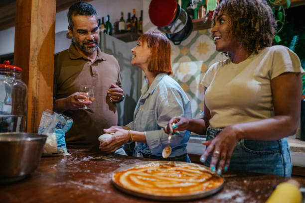 istock Mature friends drinking wine and making pizza during a dinner party 1845679225