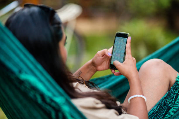 istock Young woman lying in hammock using smart phone outside on a patio at resort 1845682623