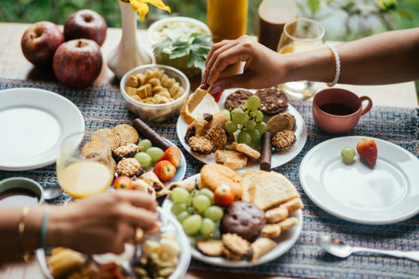 Couple drinking eating a gourmet breakfast on the patio of a BnB Close-up of two young women enjoying an assortment of food for breakfast outside on the patio of their BnB gay dinner table stock pictures, royalty-free photos & images