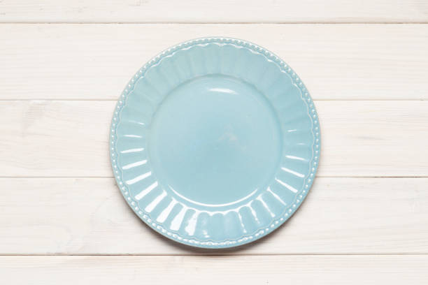 istock Empty blue plate on white wooden background. Retro toned. Top view with copy space 1845715849