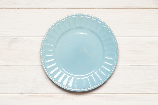 Empty blue plate on white wooden background. Retro toned. Top view with copy space