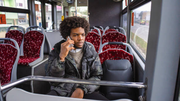 istock Male student of Black ethnicity, talking on mobile phone, while commuting with a bus 1845726865