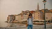 Female tourist photographing at camera against old town in Rovinj during vacation in Croatia