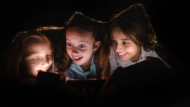 istock During sleepover, while hiding under blanket, Caucasian girls using mobile phone 1845730040