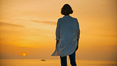 Rear view of female tourist standing against dramatic orange sky over sea during sunset in Rovinj,Croatia