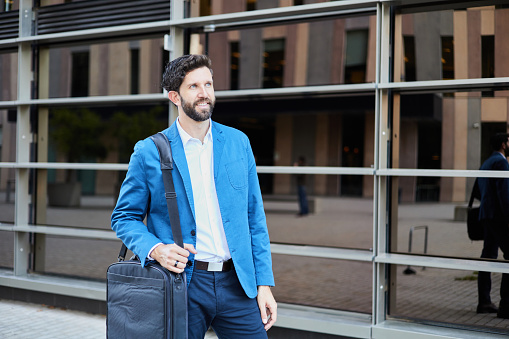 Mature businessman wearing a blue suit and carrying an office briefcase.