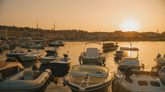 Motorboats peacefully moored in the harbor of Rovinj,Croatia,bask in the warm hues of the sunset. The scene encapsulates the serene beauty of the Adriatic