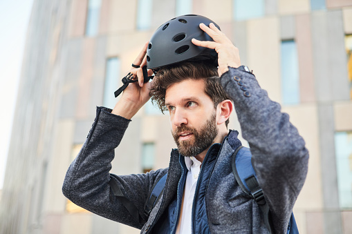 Businessman putting on a bicycle helmet in the city. Sustainable lifestyle