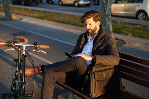 istock Smiling mature man with mobile phone sitting on city bench 1845749558