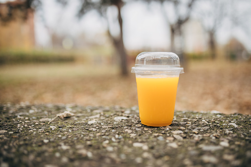 Close up of a plastic cup with juice outside in the park