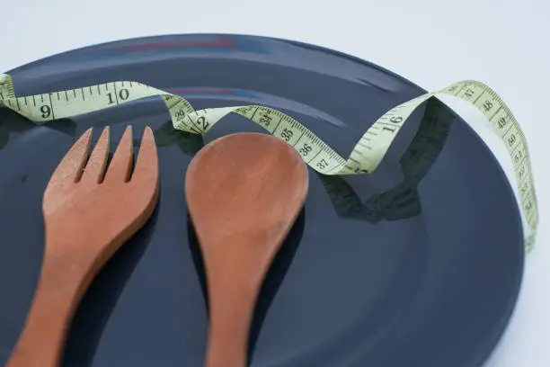 spoon and fork on the plate with measuring tape. diet concept for a healthy lifestyle
