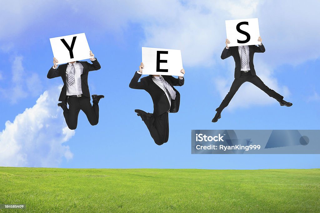 Business man happy jumping with yes text Business man happy jumping with yes text on the green grass Adult Stock Photo