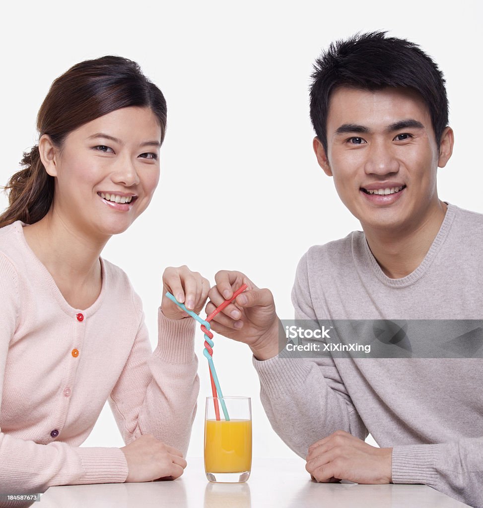 Giovane coppia condividendo un bicchiere di succo d'arancia, Fotografia da studio - Foto stock royalty-free di 25-29 anni