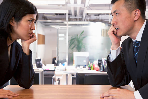 istock Two Business people staring at each other across a table 184589644