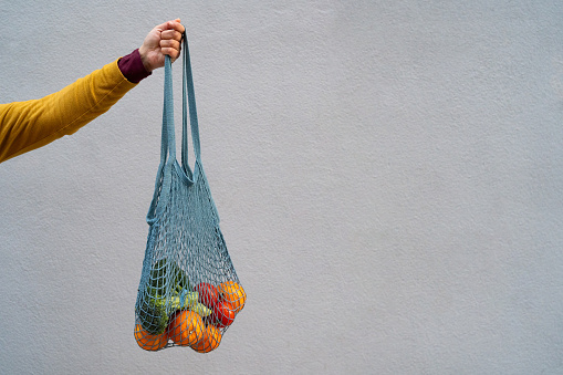 Latin woman carrying sustainable bags with fruits and vegetables