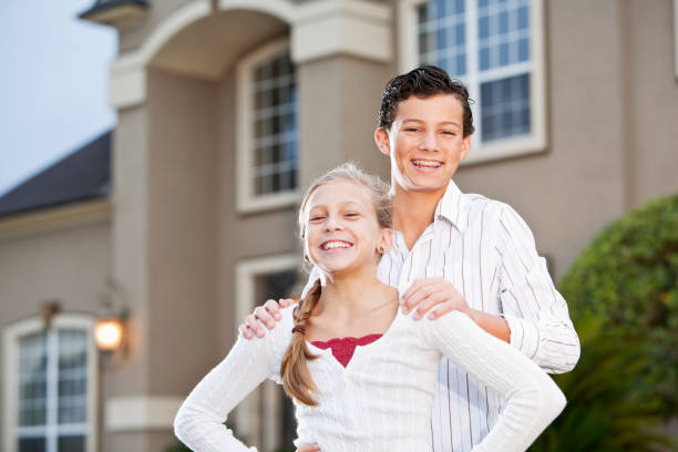 istock Brother and sister standing outside house 184591575